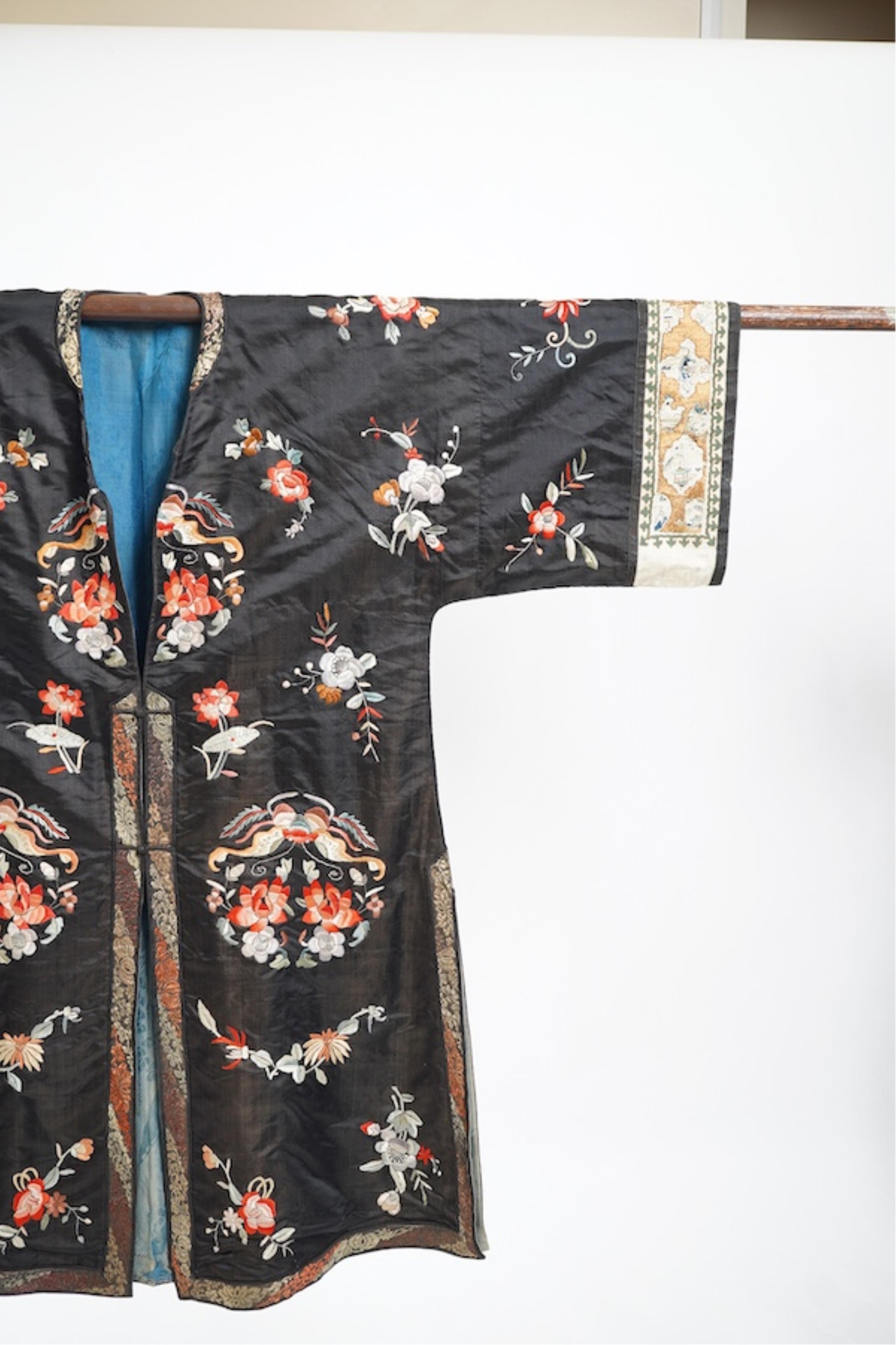 A late 19th early 20th century Chinese black silk polychrome embroidered ladies robe, decorated with cream silk, gilt and Peking knot bordered sleeve bands. The sleeve bands worked with fine figural and other embroidered